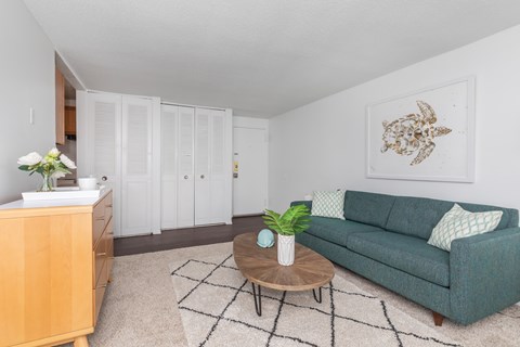 A living room with a green couch, a wooden coffee table, and a painting on the wall.