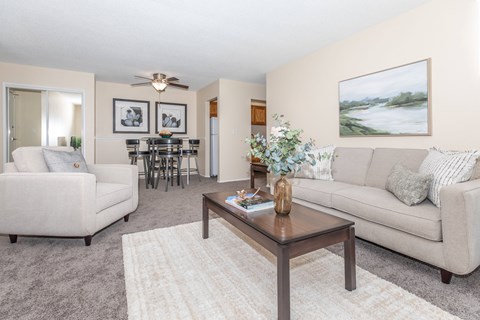A living room with a white couch, a coffee table, and a painting on the wall.