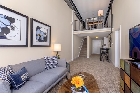 A living room with a grey couch and a coffee table with a yellow flower on it.