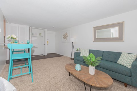 A blue chair sits in a living room with a couch and a coffee table.