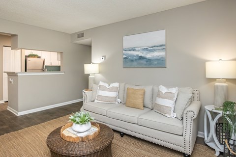 A living room with a white couch, a brown coffee table, and a painting on the wall.