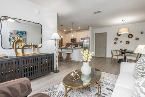 A modern living room with a glass coffee table and a large mirror on the wall.