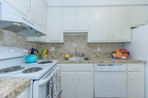 A kitchen with white cabinets and a stone backsplash.