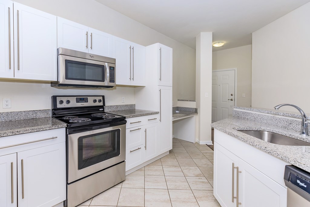 A kitchen with white cabinets and a stainless steel oven.