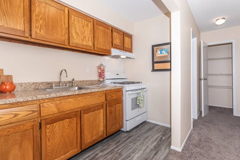 A kitchen with wooden cabinets and a white stove top oven.