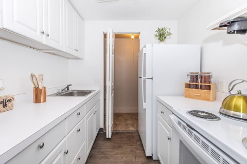 A white kitchen with a sink and a refrigerator.