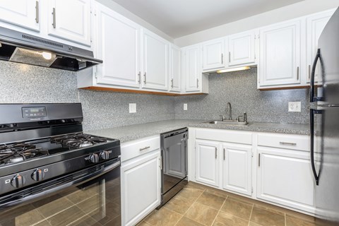 A kitchen with white cabinets and a black stove top oven.
