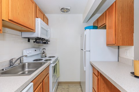 A kitchen with white appliances and wooden cabinets.