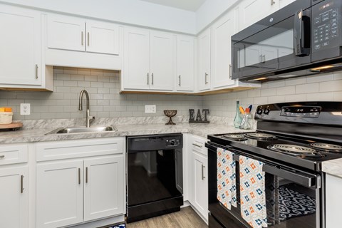 A kitchen with white cabinets and black appliances.