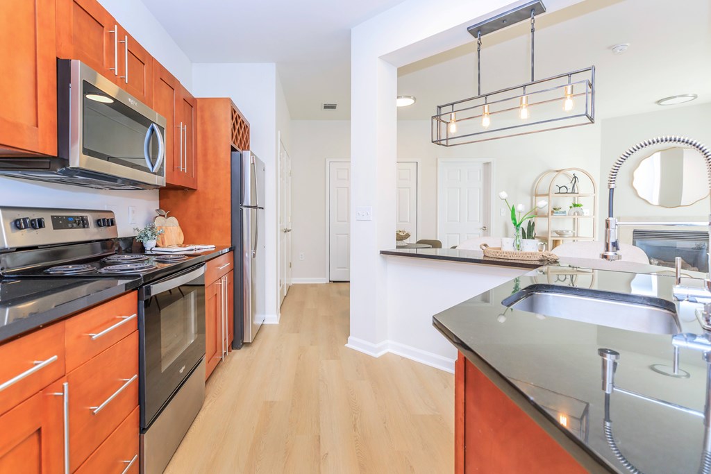 A kitchen with orange cabinets and a black stove top oven.