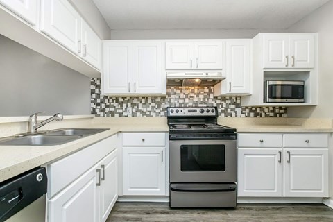 A kitchen with white cabinets and a black and white checkered backsplash.