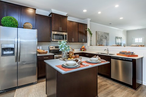 A modern kitchen with dark wood cabinets and stainless steel appliances.