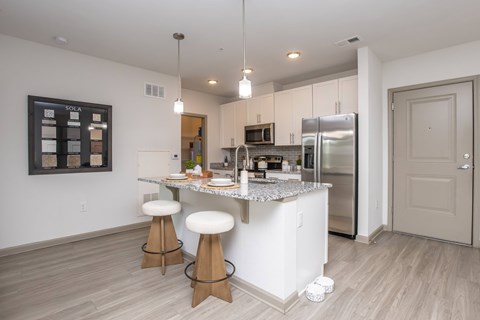 A kitchen with a white counter and stools.