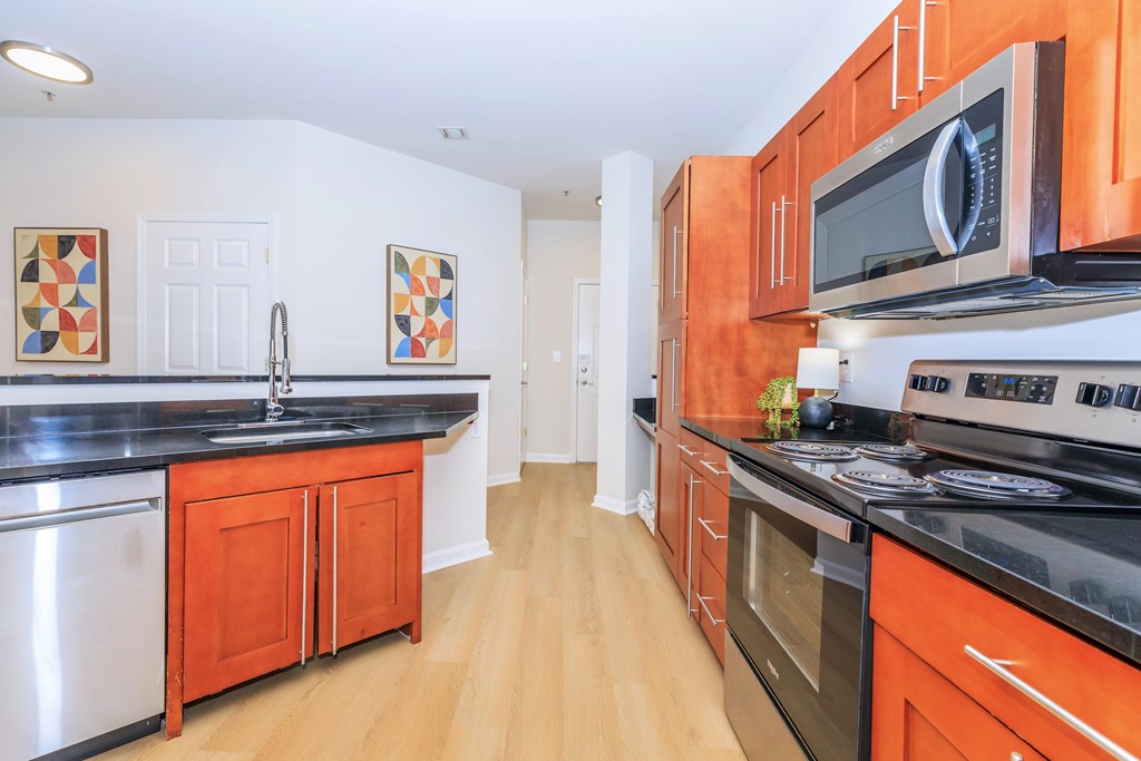A kitchen with orange cabinets and a black counter top.
