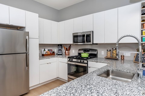 A kitchen with a stainless steel refrigerator and a granite countertop.