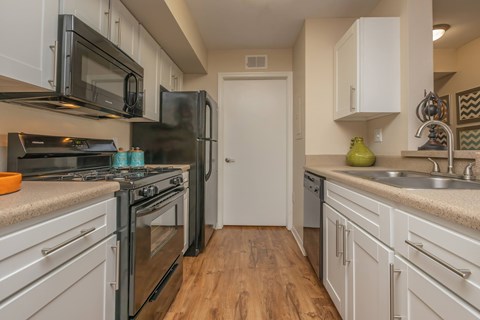 A kitchen with white cabinets and a black refrigerator.