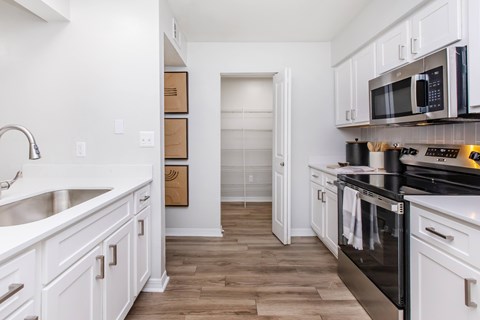 A kitchen with white cabinets and a black stove top oven.