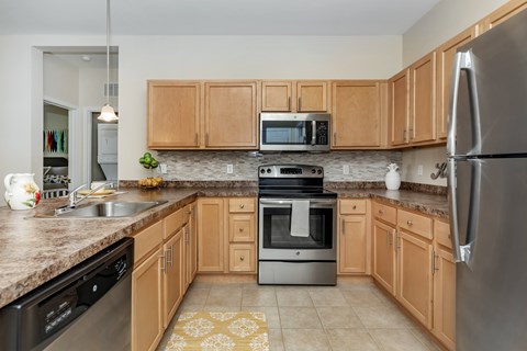 A kitchen with wooden cabinets and a stainless steel refrigerator.