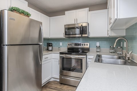 A kitchen with a stainless steel refrigerator and white cabinets.