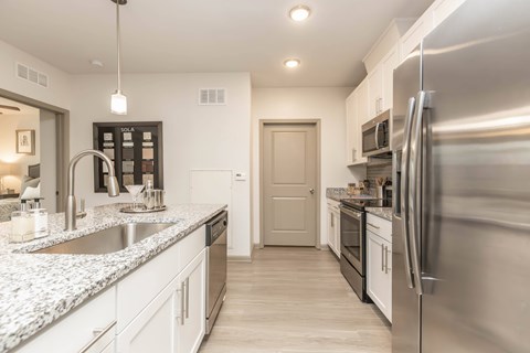 A modern kitchen with a stainless steel refrigerator and white cabinets.