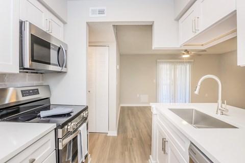 A kitchen with white cabinets and a stainless steel microwave.