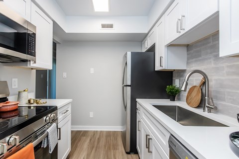 A kitchen with a black refrigerator and white cabinets.