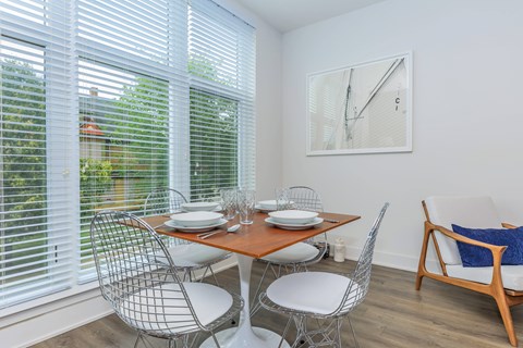 A dining room with a table set for two and a couch.