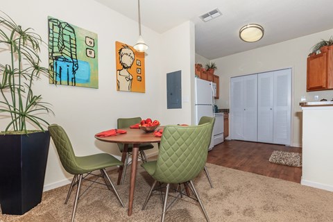 A dining room with a table set for two and a potted plant.