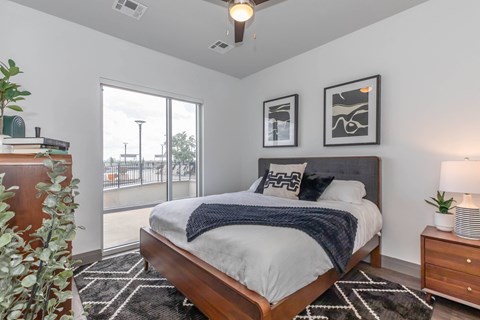 a bedroom with a large window and a bed with white sheets