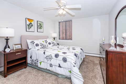 A bedroom with a bed, nightstand, and a ceiling fan.