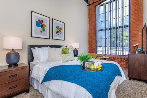 A bedroom with a bed, nightstands, and a window.
