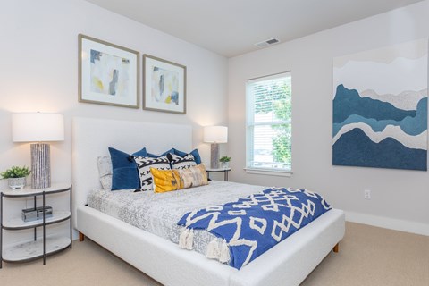 A bedroom with a large bed and two framed artworks on the wall.