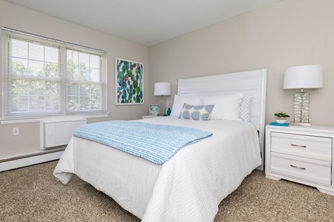 A bedroom with a white bed and a blue pillow.