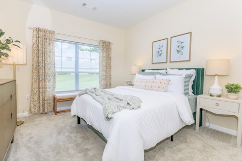 A bedroom with a large bed and a window with curtains.