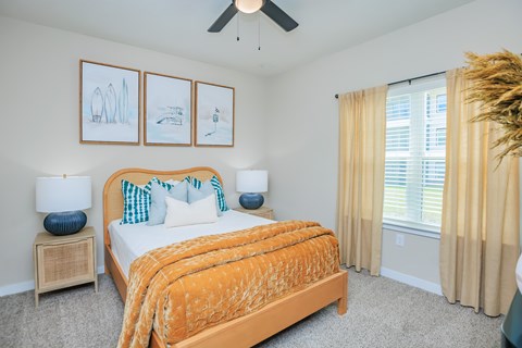 A bedroom with a bed, two lamps, and pictures on the wall.