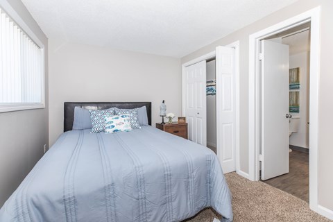A bedroom with a bed, nightstand, and closet.