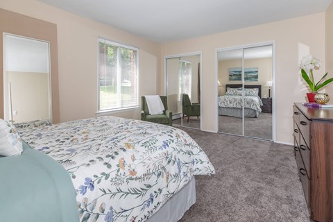 A bedroom with a large bed and a mirrored closet door.