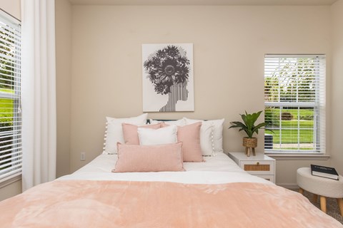 A bedroom with a large bed and a painting of a tree on the wall.