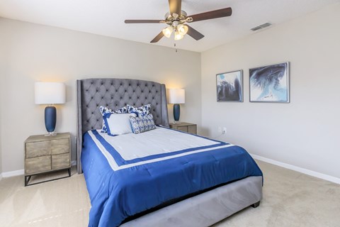 A bedroom with a large bed and a ceiling fan.