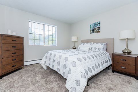 A bedroom with a bed, nightstand, and lamp.