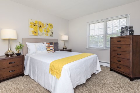 A bedroom with a white bed and a yellow throw blanket.