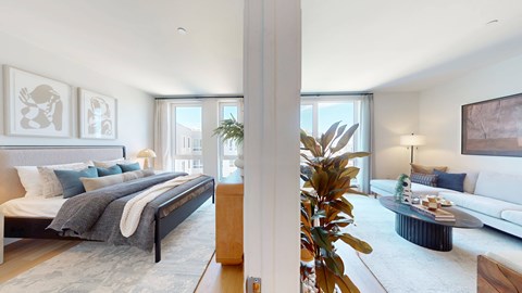 A bedroom with a large bed and a living room with a couch.