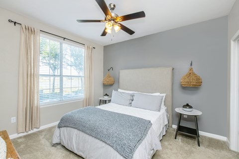 A bedroom with a large bed and a ceiling fan.