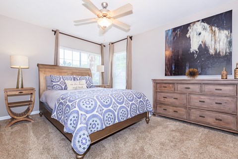 A bedroom with a bed, dresser, and ceiling fan.