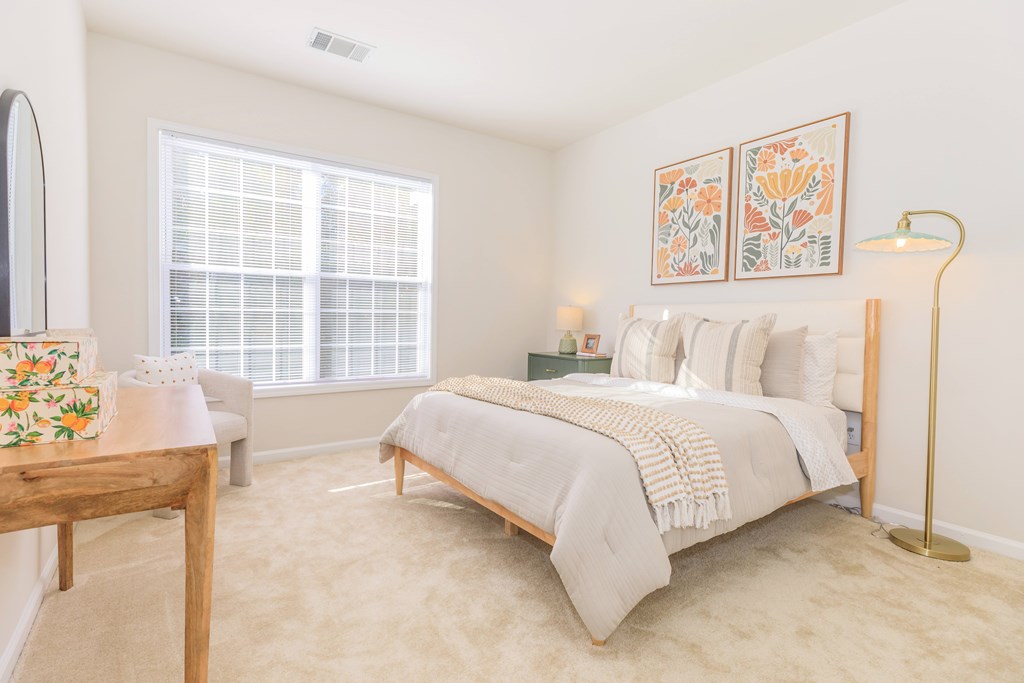 A bedroom with a bed, a nightstand, a lamp, and a window.