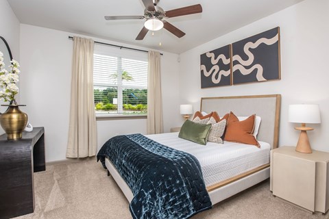 A bedroom with a bed, nightstands, and a ceiling fan.