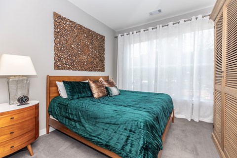 A bedroom with a bed, nightstand, and a wooden wall art.