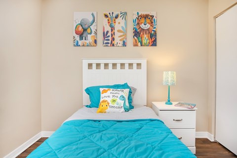 A bedroom with a white bed and a blue comforter.