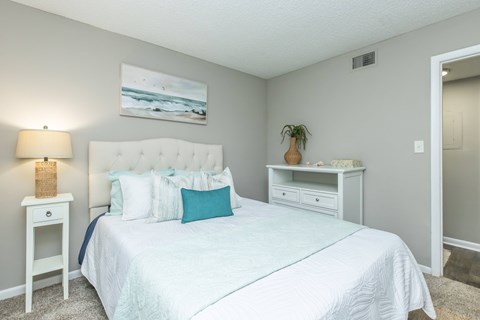 A bedroom with a large bed and a painting on the wall.