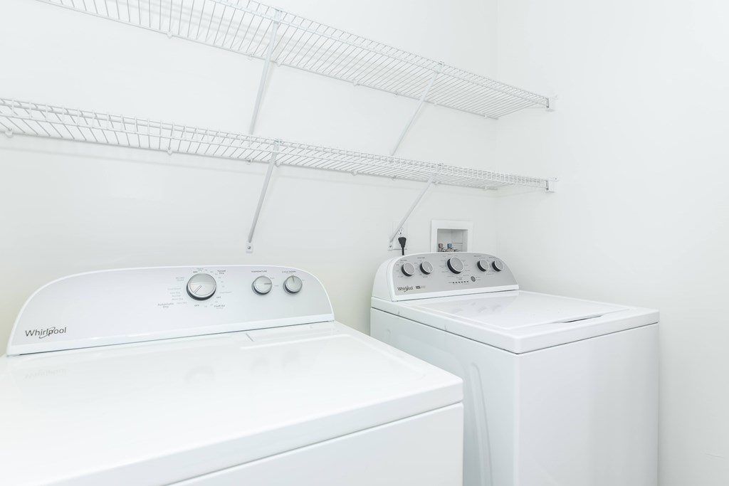 Two white washing machines in a laundry room.